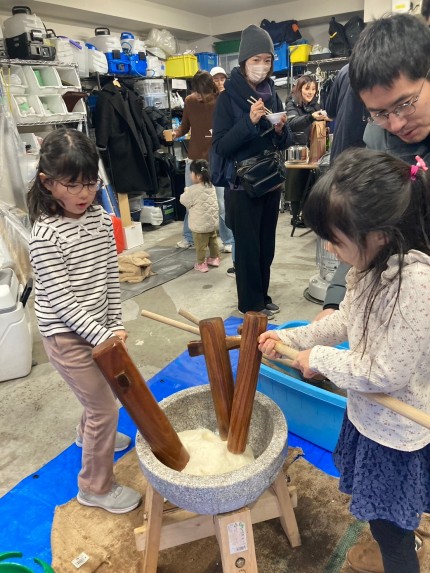 みんなで杵を使って餅米をこねる体験